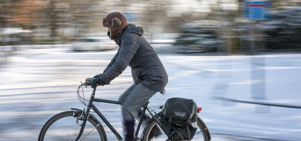 Radfahrer fährt vor einer verschneiten Wiese Radfahrer fährt vor einer verschneiten Wiese