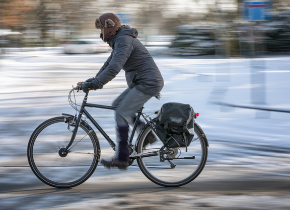 Radfahrer fährt vor einer verschneiten Wiese
