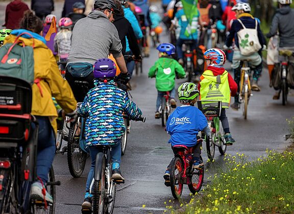 Kinder und Erwachsene fahren gemeinsam auf einer Straße Fahrrad