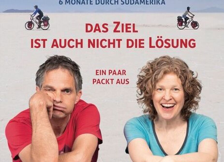 Kabarett-Duo Reisegruppe-Ehrenfeld Ein Mann und eine Frau stützen sich auf ihren Fahrradhelmen ab und lächeln in die Kamera