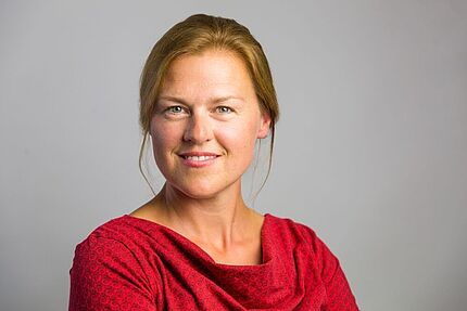 Porträtaufnahme von Barbara Körbs vor grauem Hintergrund.