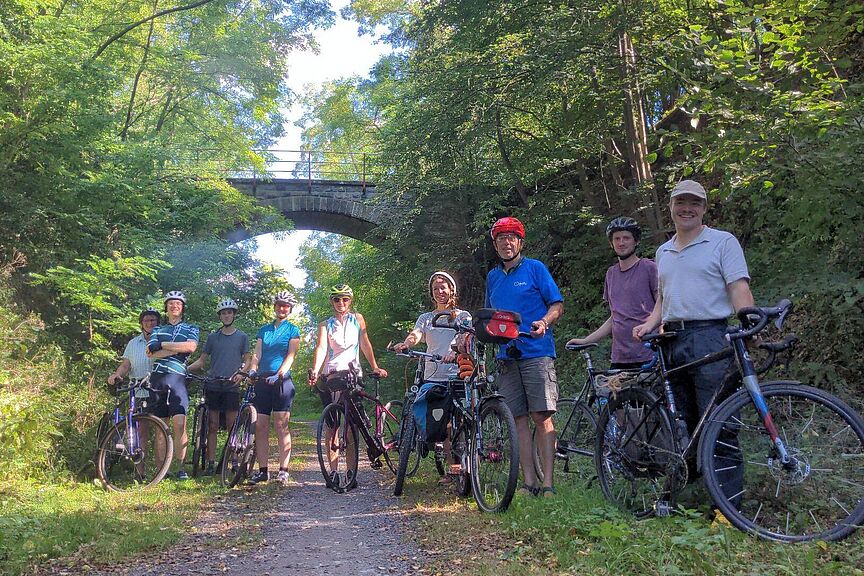 Vernetzungsradtour SHK Radfahrer auf einem Waldweg vor einer Brücke