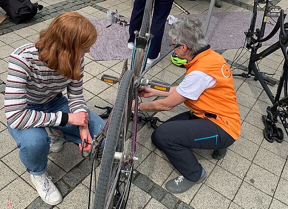 Eine Frau vom ADFC und eine Studierende arbeiten an einem Fahrrad