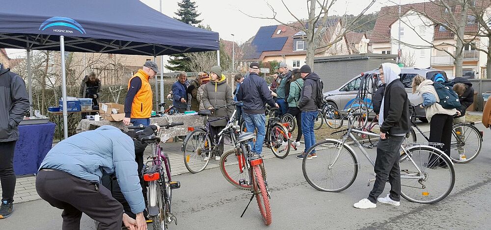 Fahrrad-Benefiz-Aktion Januar 2025 Menschen beugen sich über Fahrräder und diskutieren miteinander