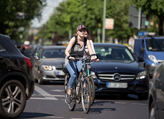 Frau auf Fahrrad in dichtem Autoverkehr
