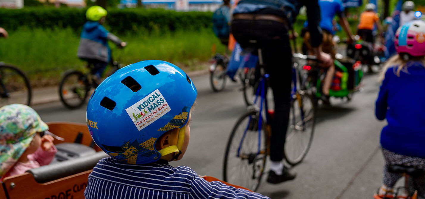 Kleinkind auf einem Fahrrad, auf seinem Helm steht Kidical Mass