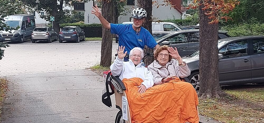 Fahrrad-Rikscha Zwei Damen werden in einer Fahrrad-Rikscha gefahren und winken fröhlich