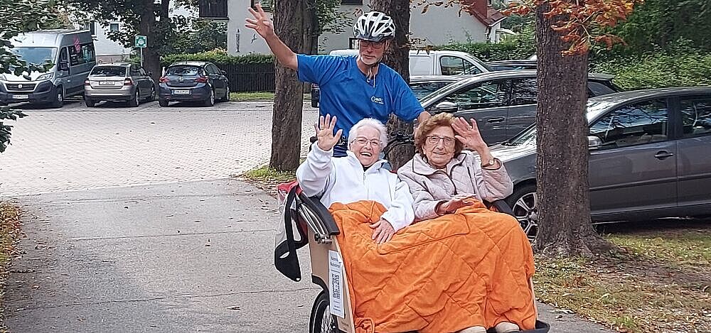 Zwei Frauen werden in einer Fahrrad-Rikscha gefahren und winken Zwei Frauen werden in einer Fahrrad-Rikscha gefahren und winken