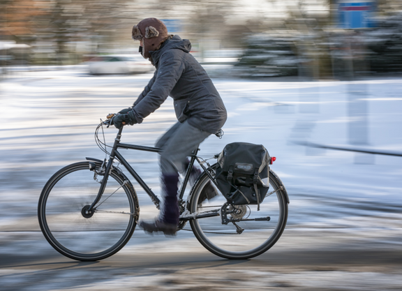Frau auf Fahrrad vor einer Winterlandschaft.